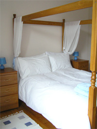 Front bedroom with four poster bed and an original iron fireplace with tile surround and a view to Marchmont crescent